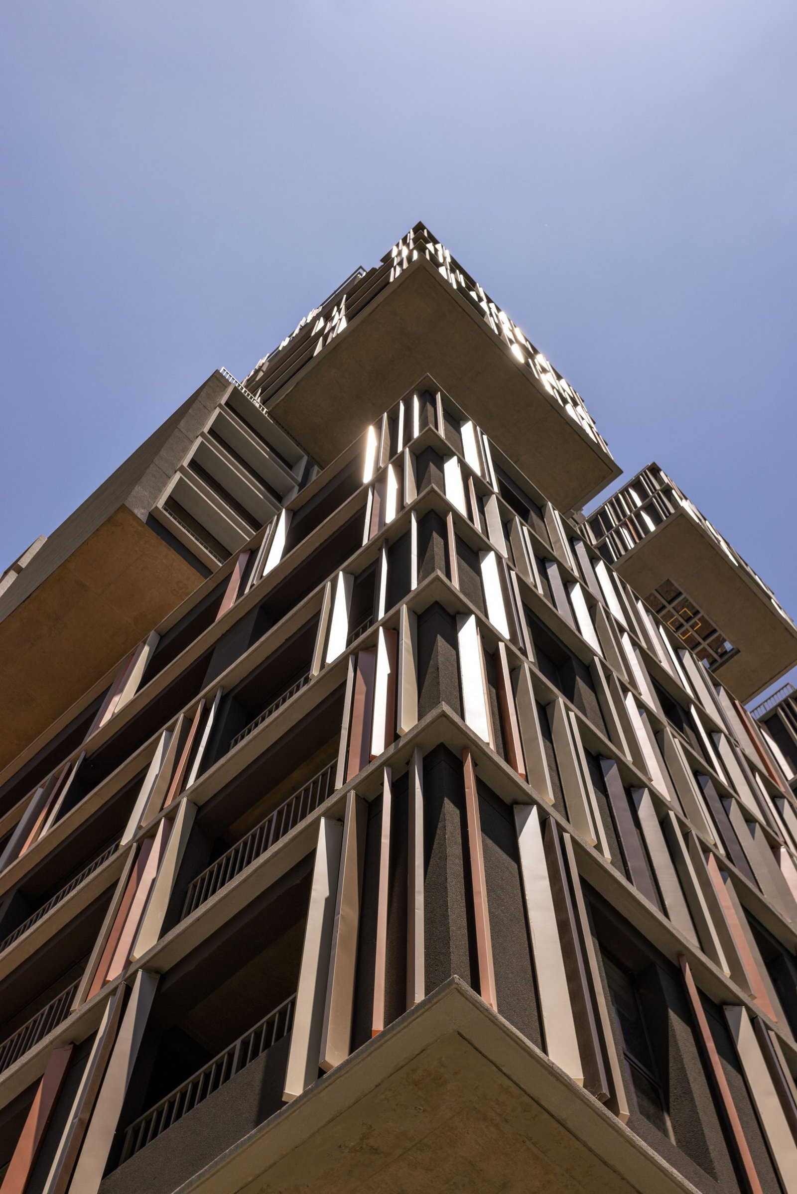 Fachada moderna do edifício On Melo Alves vista de baixo contra um céu azul limpo.